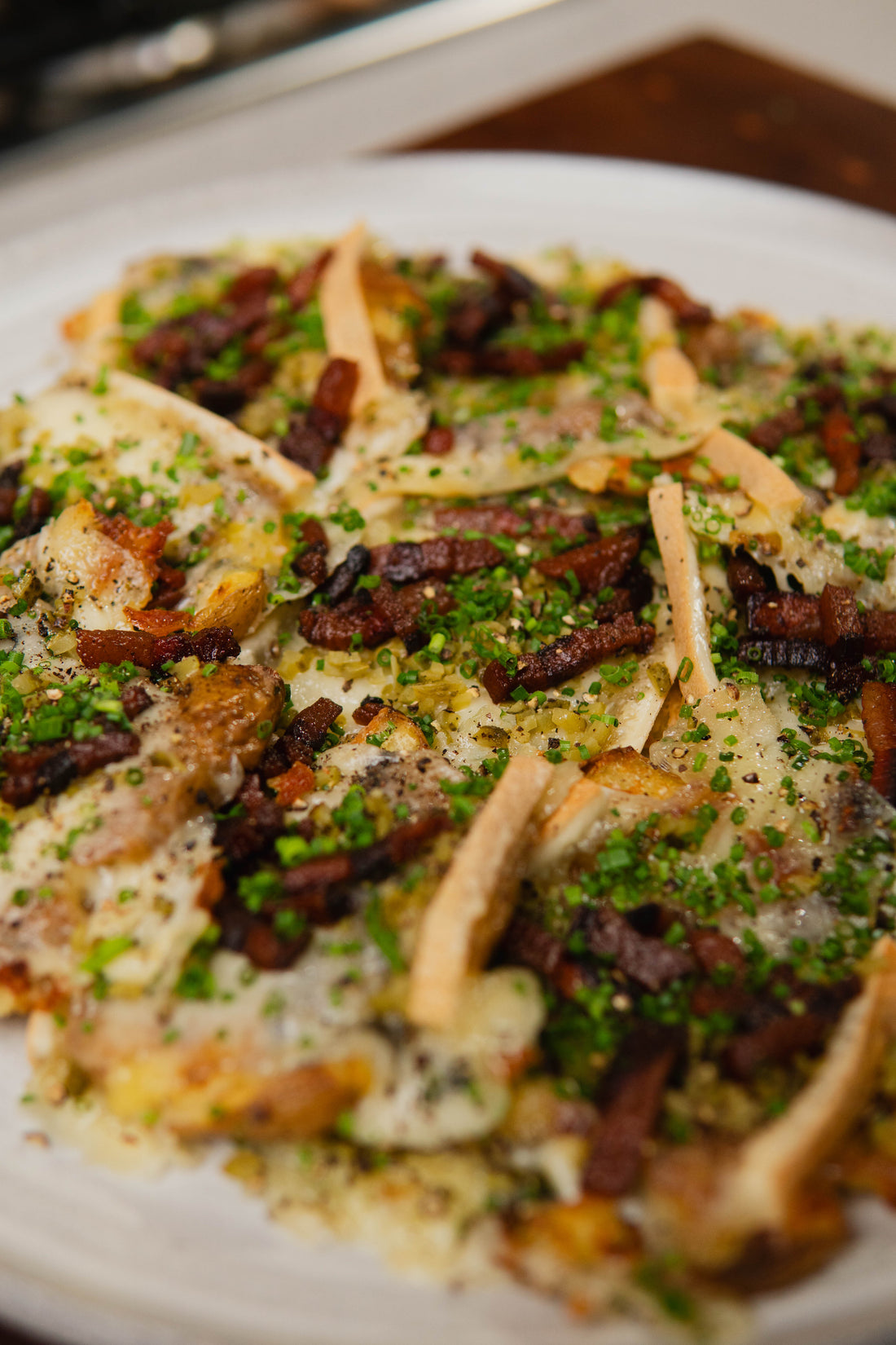 CRISPY SMASHED POTATOES WITH RACLETTE, GUANCIALE & CORNICHONS